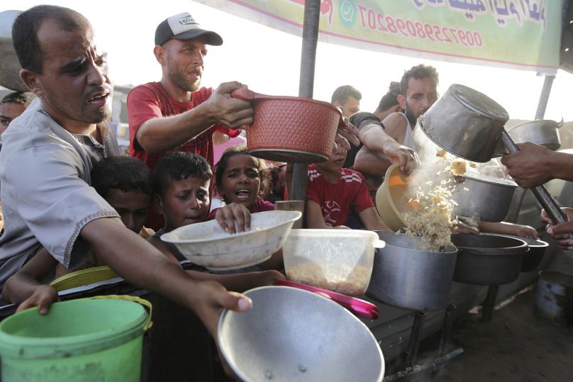 Os palestinianos recolhem ajuda alimentar antes do feriado de Eid al-Adha em Khan Younis, na Faixa de Gaza