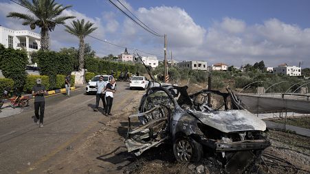 Palestinians gather around a car destroyed in a drone strike Zeita village, north of the West Bank city of Tulkarem.