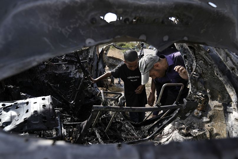 Palestinos inspeccionan el automóvil destruido en el que presuntamente viajaban cinco militantes palestinos al norte de la ciudad cisjordana de Tulkarem.