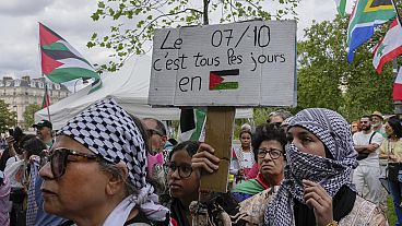 A protester wearing a keffiyeh holds a placard that reads, "The 7 of October is every day in Palestine" during a gathering in support of Palestinian people in Gaza, in Paris, 