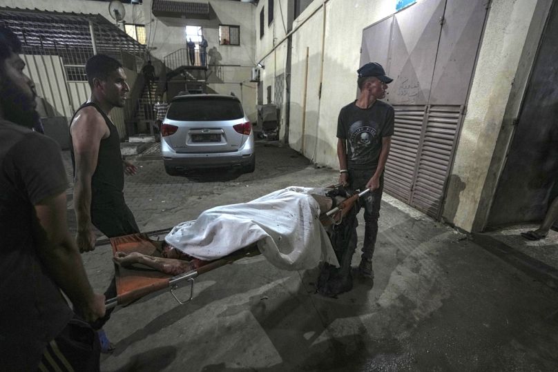 Palästinenser tragen die Leiche eines Opfers eines israelischen Angriffs, bei dem ein Zeltplatz im Hof ​​des Al-Aqsa-Krankenhauses in Deir al Balah getroffen wurde.