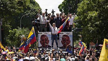 Opposition leader Maria Corina Machado holds a national flag while waving to supporters as she arrives for a rally in Caracas, Venezuela, Saturday, Aug. 3, 2024