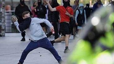 A demonstrator throws a brick during a protest in Liverpool, England, on Saturday, Aug. 3, 2024, following Monday's stabbing attacks in Southport, in which three young childre