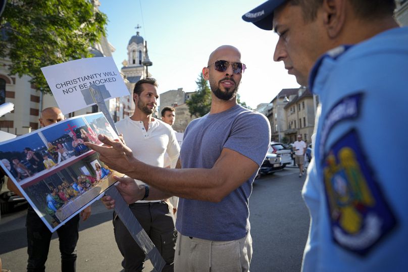 Social media influencer Andrew Tate points to a picture of a scene that took place during the Paris Olympics opening ceremony.