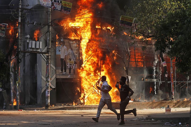 Bangladeş'te hükümet karşıtı protestolarda hayatını kaybedenler için düzenlenen miting sırasında protestocularca ateşe verilen bir alışveriş merkezi.