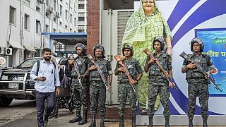 Militari davanti a un ritratto dell'ex Prima Ministra Sheikh Hasina nella giornata di lutto nazionale per ricordare le vittime degli scontri nel Paese, Dacca, Bangladesh