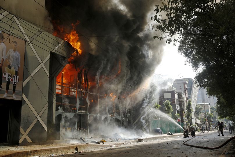 Bombeiros apagam um incêndio num centro comercial que foi incendiado por manifestantes durante uma manifestação contra a primeira-ministra Sheikh Hasina e o seu governo.