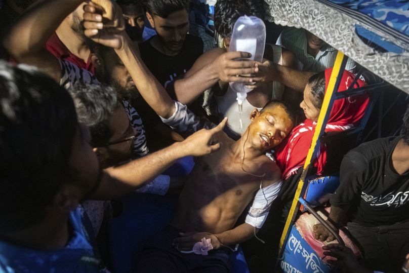 Pessoas ajudam um homem, que ficou ferido durante os protestos antigovernamentais no Bangladesh, a sair de um veículo num hospital em Dhaka, Bangladesh.