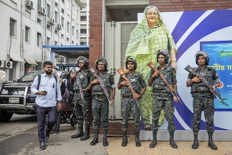 Militares montam guarda em frente a um grande retrato recortado da primeira-ministra Sheikh Hasina durante o dia de luto nacional, declarado pelo governo do Bangladesh.