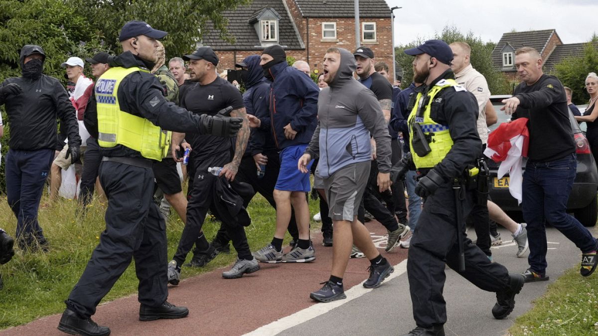 Des policiers font face à des manifestants devant le Holiday Inn Express à Rotherham, en Angleterre, dimanche 4 août 2024. 