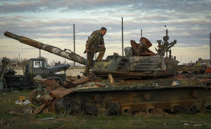 A Ukrainian soldier inspects a damaged Russian tank in the recently retaken village Chornobaivka near Kherson, 15 November 2022