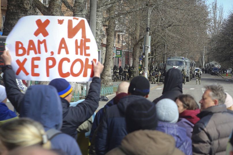 Civili ucraini di fronte ai soldati russi durante una manifestazione contro l'occupazione di Mosca a Kherson, 14 marzo 2022