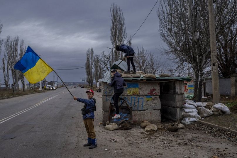 Des enfants ukrainiens jouent à un poste de contrôle abandonné à Kherson, le 23 novembre 2022.