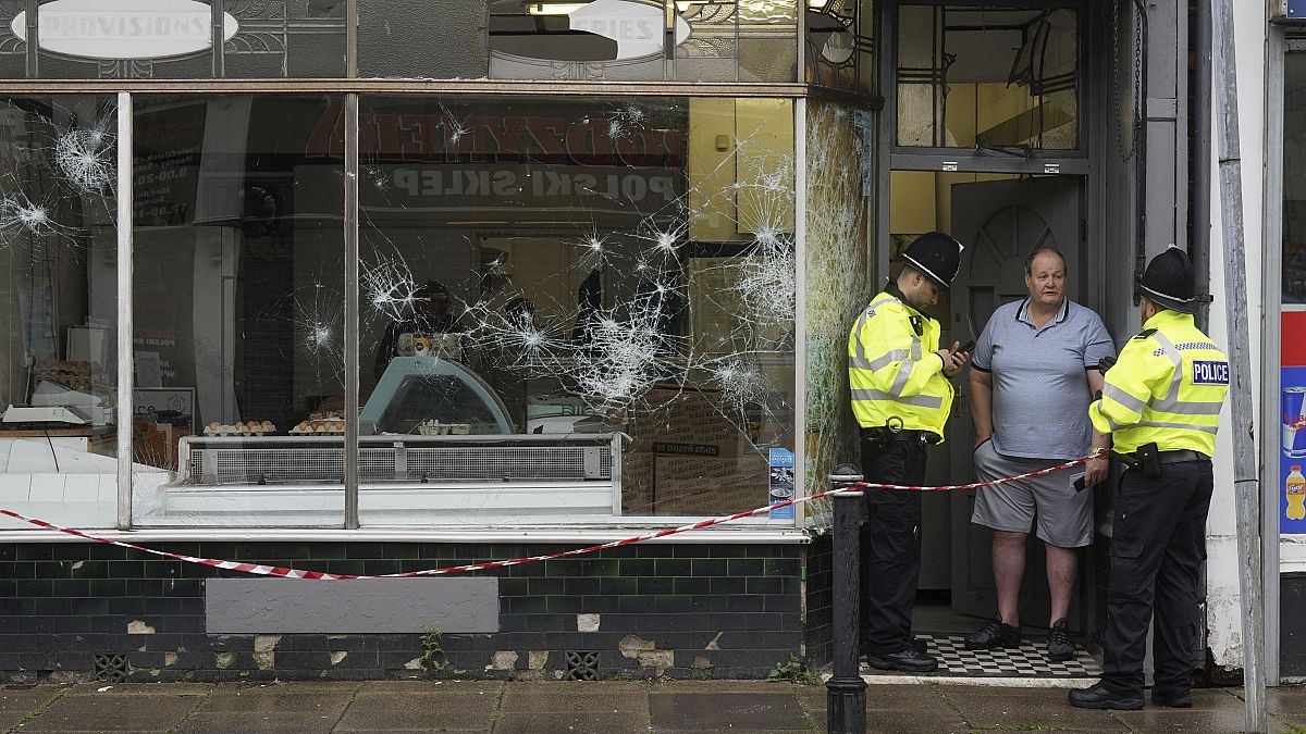 Agentes de Policía frente a una carnicería dañada en Murray Street en Hartlepool, Inglaterra, el jueves 1 de agosto de 2024, tras una violenta protesta el día anterior.