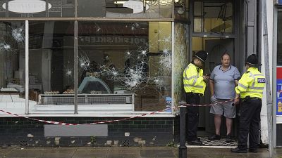 Agentes de Policía frente a una carnicería dañada en Murray Street en Hartlepool, Inglaterra, el jueves 1 de agosto de 2024, tras una violenta protesta el día anterior.