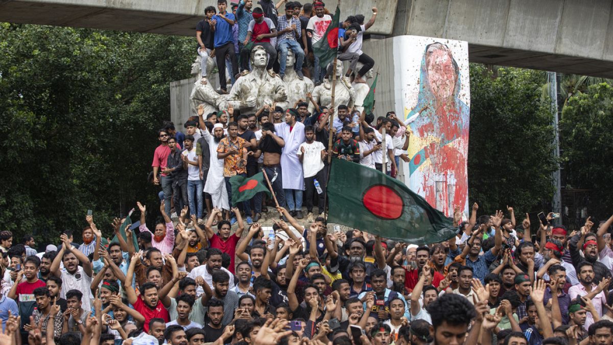 Manifestantes sobem a um monumento público enquanto celebram a notícia da demissão da primeira-ministra Sheikh Hasina, em Daca, Bangladesh, segunda-feira, 5 de agosto de 2024