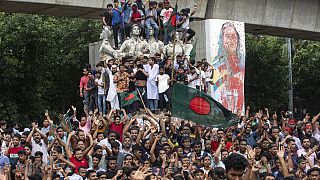 Des manifestants escaladent un monument public alors qu'ils célèbrent la nouvelle de la démission de la Première ministre Sheikh Hasina, à Dhaka, au Bangladesh, le lundi 5 août 2024. 