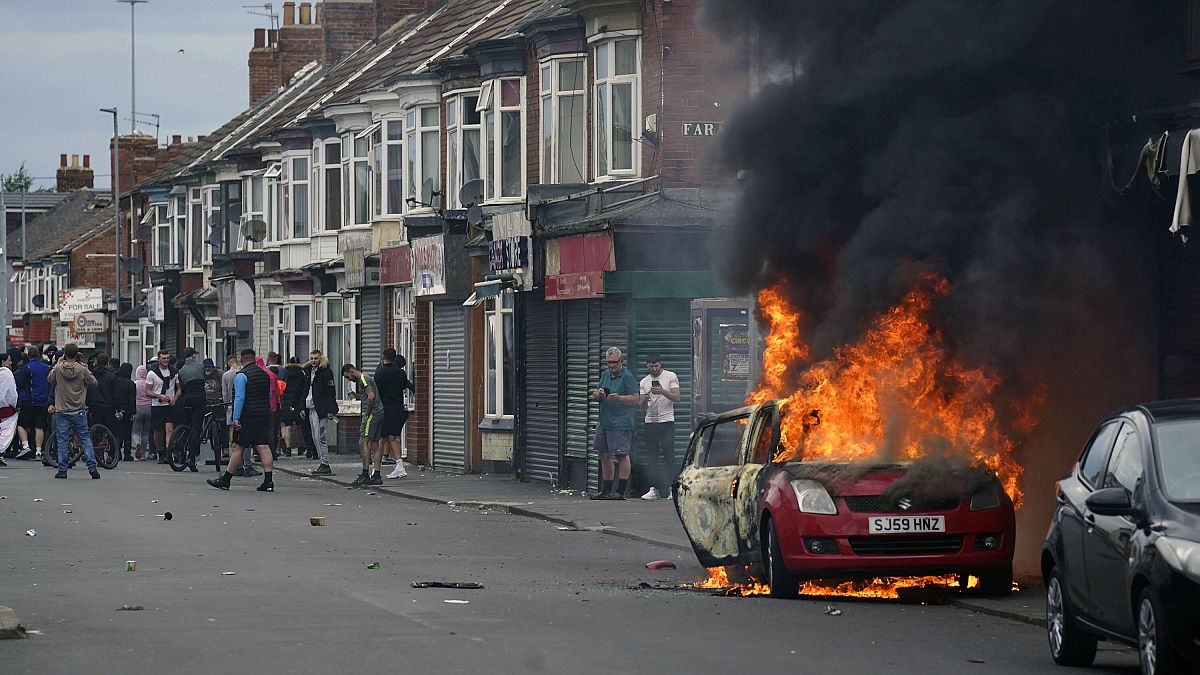 Un automóvil arde durante una protesta contra la inmigración en Middlesbrough, Inglaterra, el domingo 4 de agosto de 2024