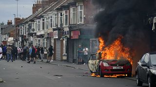 Un automóvil arde durante una protesta contra la inmigración en Middlesbrough, Inglaterra, el domingo 4 de agosto de 2024