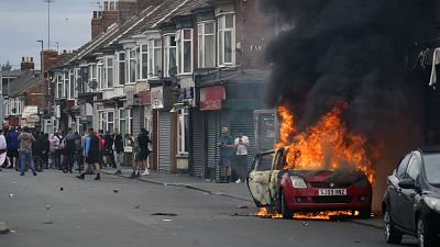 Un automóvil arde durante una protesta contra la inmigración en Middlesbrough, Inglaterra, el domingo 4 de agosto de 2024