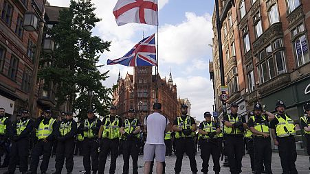 Agentes da polícia enfrentam um manifestante solitário com bandeiras inglesas e britânicas durante um protesto na Praça do Mercado de Nottingham, Inglaterra