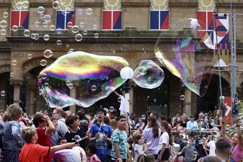 Populares sopram bolas de sabão à porta da Câmara Municipal durante uma vigília em memória das vítimas do ataque em Southport