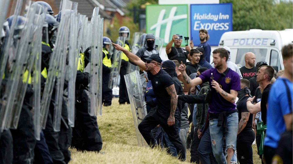 Manifestantes enfrentam agentes da polícia durante um protesto anti-imigração no exterior do Holiday Inn Express em Rotherham, Inglaterra, no domingo, 4 de agosto de 2024.