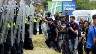 Demonstrators face police officers as trouble flares during an anti-immigration protest outside the Holiday Inn Express in Rotherham, England, Sunday Aug. 4, 2024.