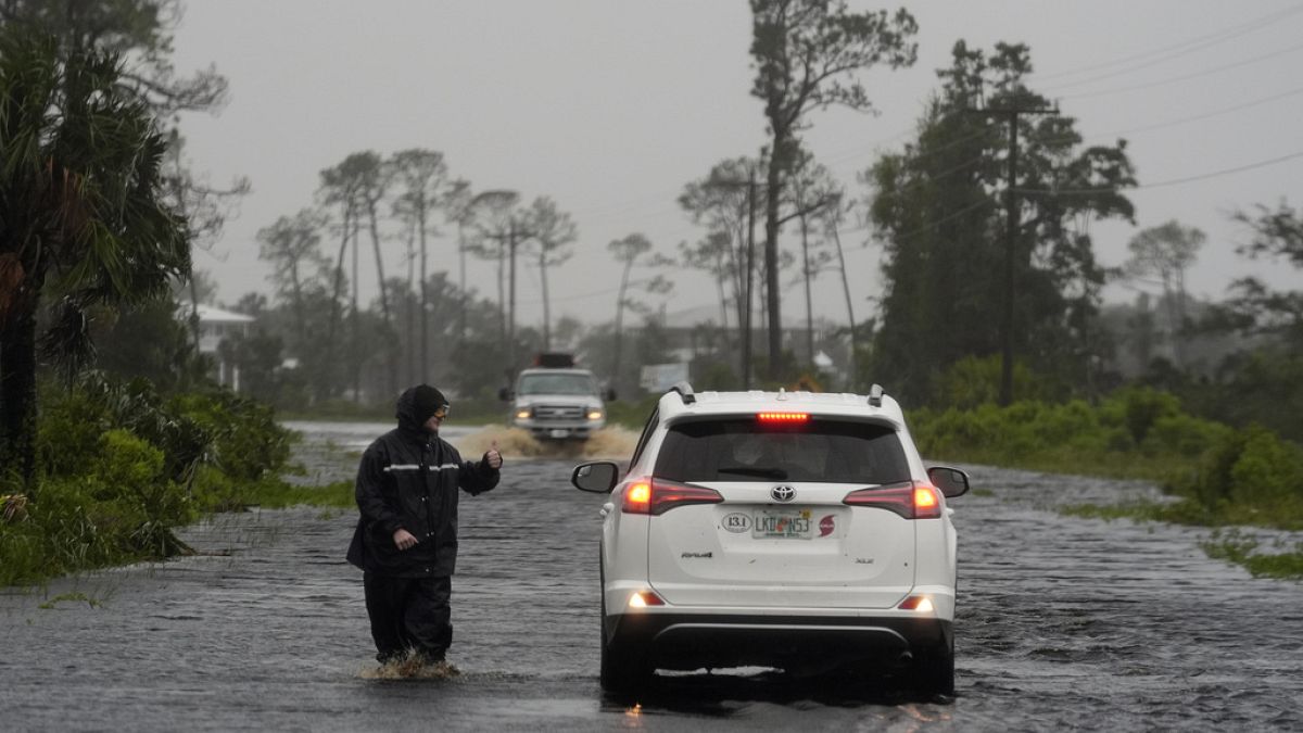 Un homme marche sur la route inondée de Horseshoe Beach, en Floride, le lundi 5 août 2024. 