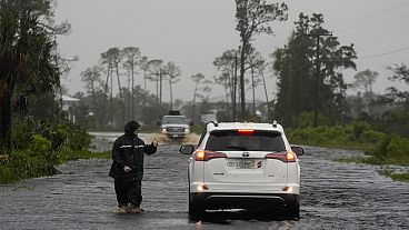 Um homem caminha através da tempestade na estrada inundada para Horseshoe Beach, na Flórida, na manhã de segunda-feira, 5 de agosto de 2024. 