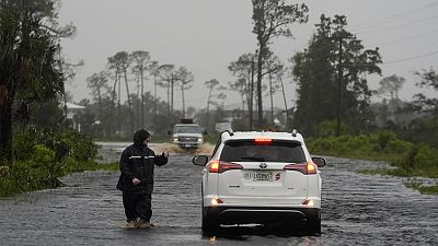 A man walks through storm surge on the flooded road into Horseshoe Beach, Fla., Monday morning, Aug. 5, 2024. 