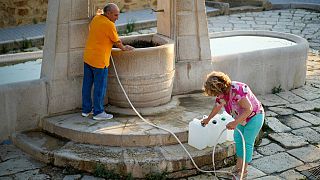 Antonino Contino, left, and his wife Antonella Croce fill jerry cans with water for daily use at Agrigento's only public fountain in Sicily, on 17 July 2024.