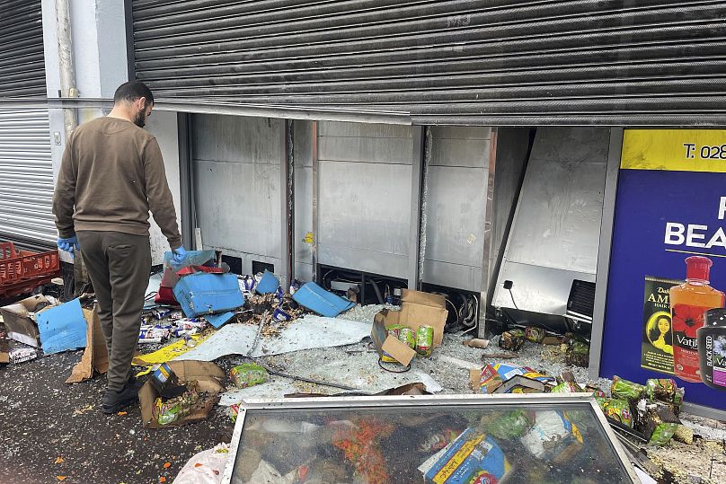 A man tries to clean up a supermarket damaged by fire on Donegall Road in Belfast on Saturday.