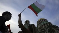 FILE - A pro-government protester holds a Bulgarian flag during a demonstration in support of incumbent Bulgarian government near the Bulgarian Parliament building in Sofia, T