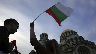 FILE - A pro-government protester holds a Bulgarian flag during a demonstration in support of incumbent Bulgarian government near the Bulgarian Parliament building in Sofia, T