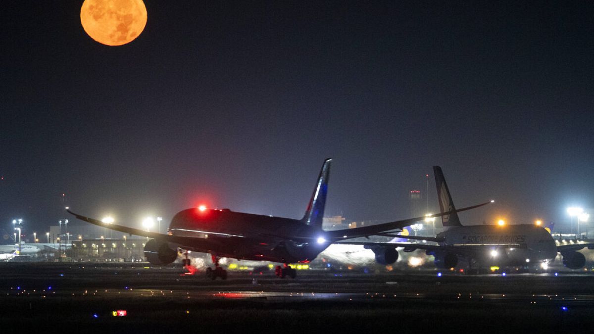 Um avião A380 aterra ao lado de outro A380 enquanto a lua cheia brilha no aeroporto internacional de Frankfurt, Alemanha, no domingo, 13 de outubro de 2019. 