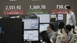 Currency traders watch monitors near a screen on 6 August 2024