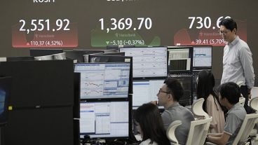 Currency traders watch monitors near a screen on 6 August 2024