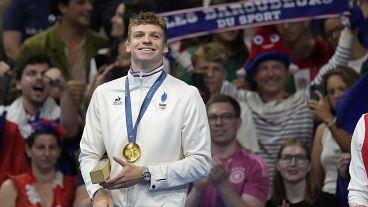 Leon Marchand of France, reacts as he stands on the podium after receiving his gold medal for the men's 200-meter individual medley final at the 2024 Summer Olympics.