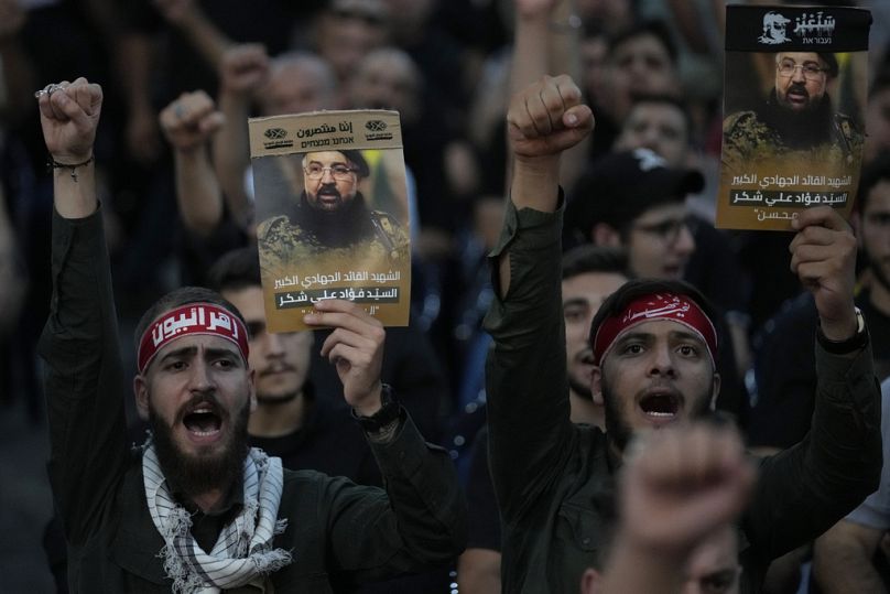 Hezbollah supporters shout slogans and hold up portraits that show the top commander Fouad Shukur in a southern suburb of Beirut, Lebanon, Aug. 1, 2024.