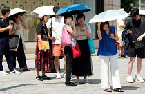 Pedestrian holding parasols stand under an intense sun at Ginza shopping street in Tokyo, on 8 July 2024.