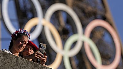 Une personne prend un selfie avec les anneaux olympiques sur la Tour Eiffel pendant les Jeux Olympiques d'été de 2024, le mardi 6 août 2024, à Paris, en France.