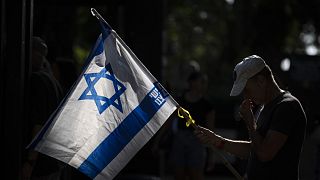 Un hombre sostiene una bandera israelí.