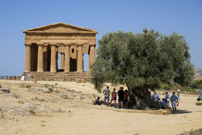 Des visiteurs admirent l'ancien temple grec de Concordia, connu sous le nom de temple de Junon, à Agrigente, dans le sud de la Sicile