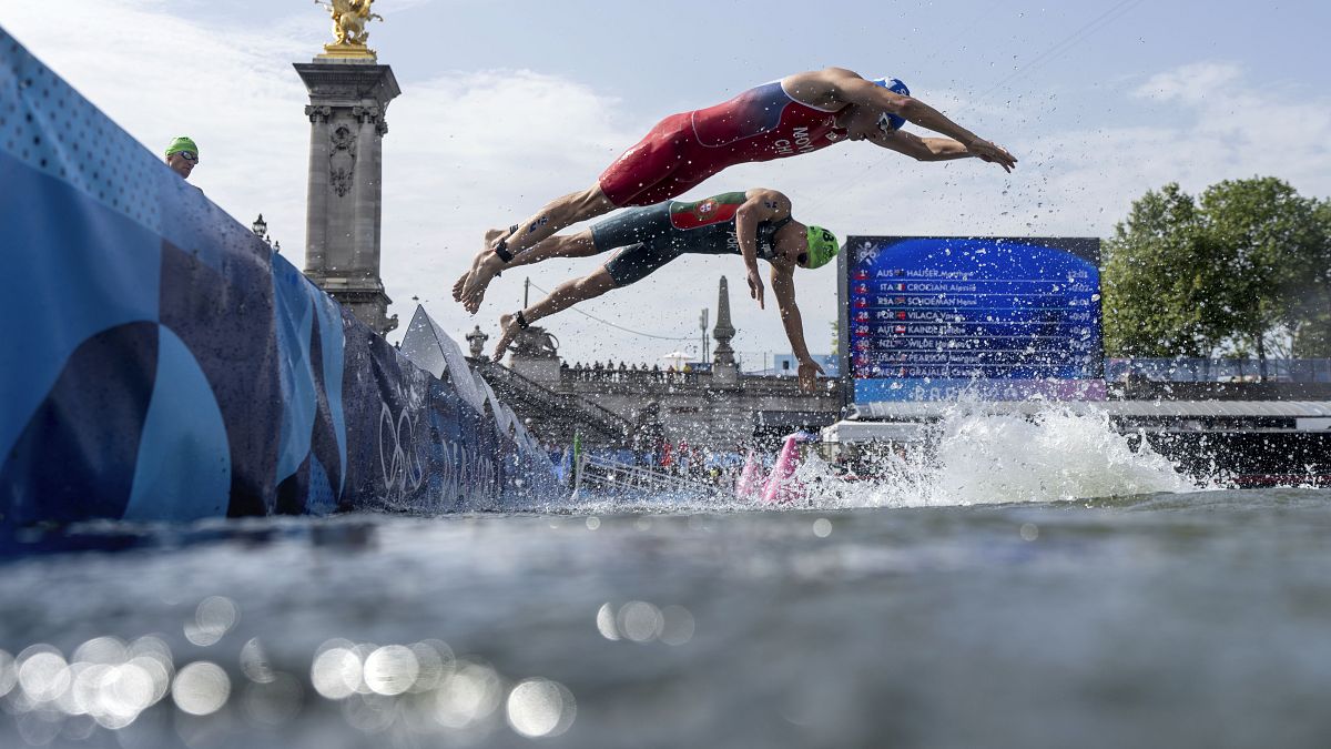 El chileno Diego Maya, a la derecha, y el portugués Vasco Vilaça se zambullen de nuevo en el río Sena para la segunda vuelta de la parte de natación en la competición individual masculina de triatlón.