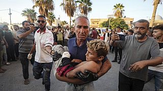 Um homem palestiniano carrega uma criança ferida após um ataque aéreo israelita em Deir al Balah, na Faixa de Gaza, terça-feira, 6 de agosto de 2024.