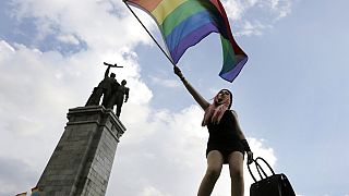 Un attivista sventola una bandiera arcobaleno davanti al Monumento dell'esercito sovietico, durante la parata del Sofia Gay Pride a Sofia, sabato 27 giugno 2015.