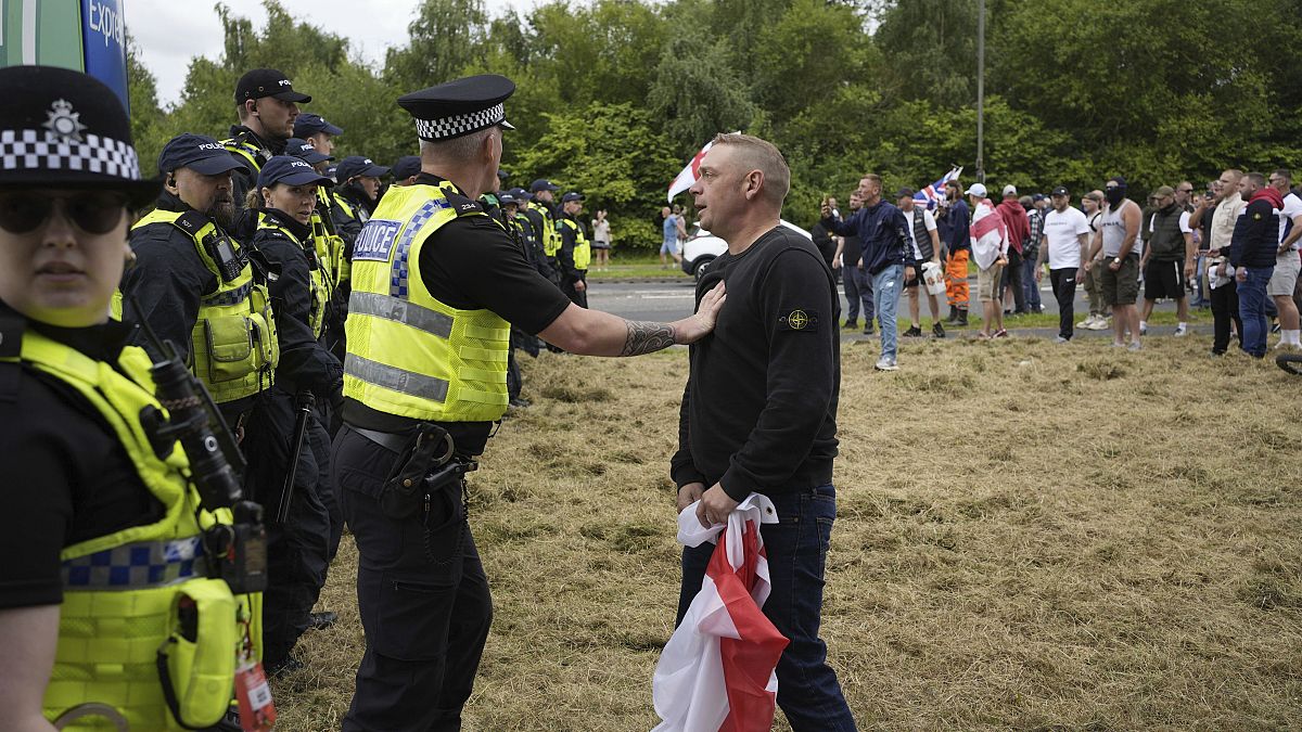 Polizisten stehen Demonstranten vor dem Holiday Inn Express in Rotherham, England, am Sonntag, 4. August 2024, gegenüber.