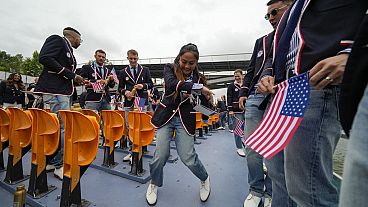 Logan Edra, of the United States breakdancing team, dances as she travels along with teammates on the Seine River in Paris, France, during the opening ceremony.