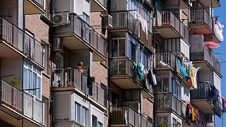 Uma mulher pendura roupa para secar na varanda de um bloco habitacional em Madrid, Espanha.